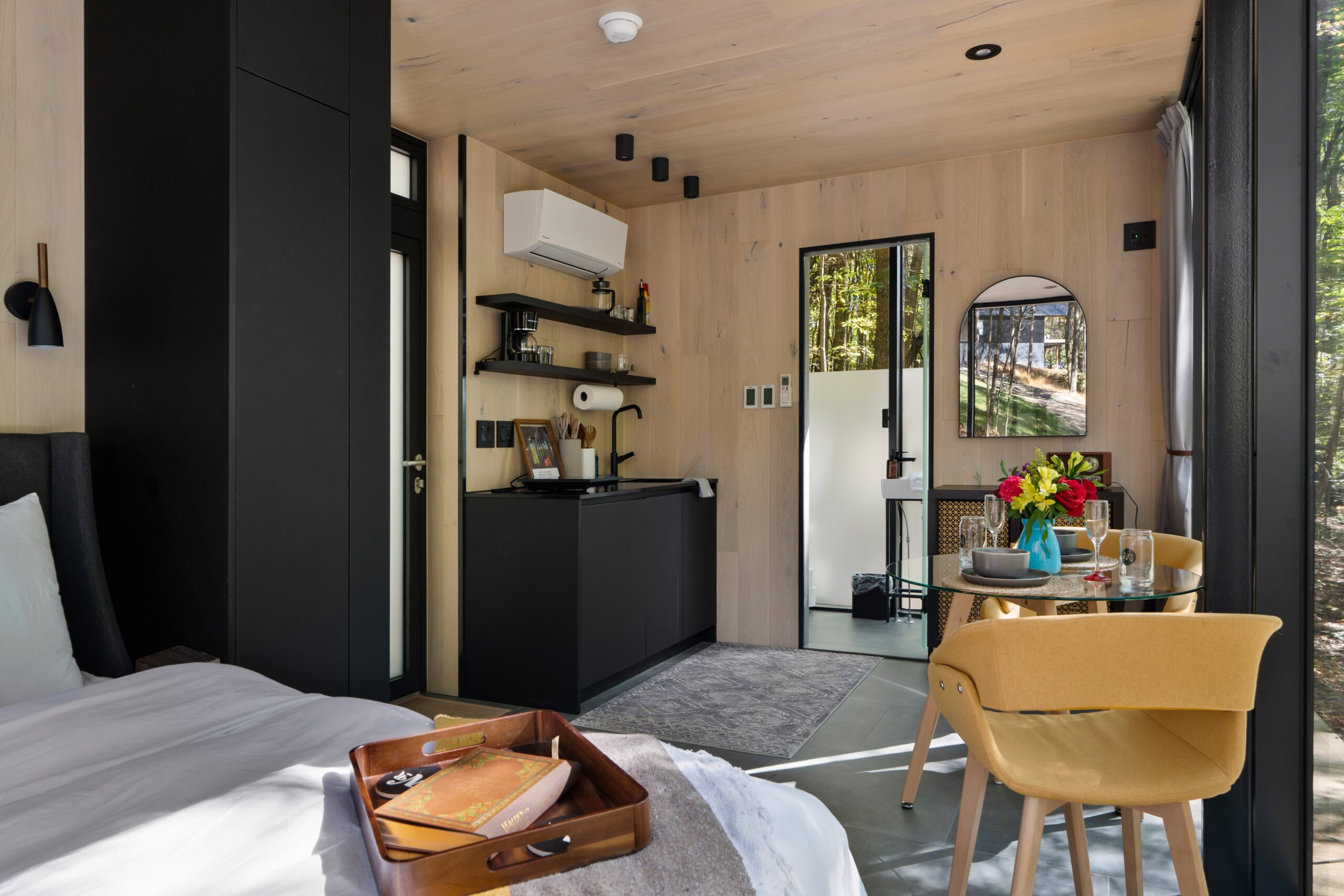 Thoreau mirror home interior in Hocking Hills — bed facing floor-to-ceiling forest glass
